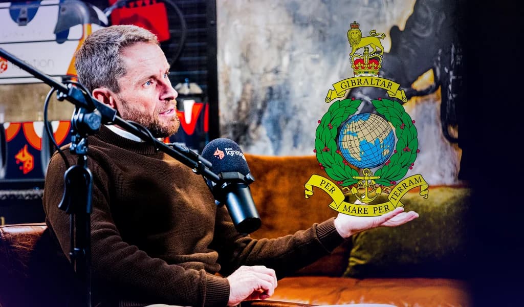 Richard Browning speaking into a microphone in a studio, with the Gibraltar coat of arms displayed beside him.