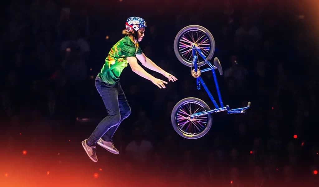 BMX rider mid-air releasing their bike against a dark background.