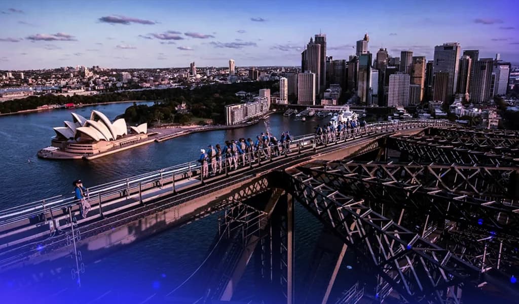 Group of people climbing the Sydney Harbour Bridge with the Opera House and city skyline in the background.