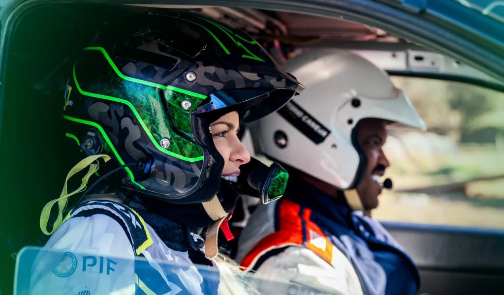 Rally driver and co-driver wearing helmets communicating inside a rally car.