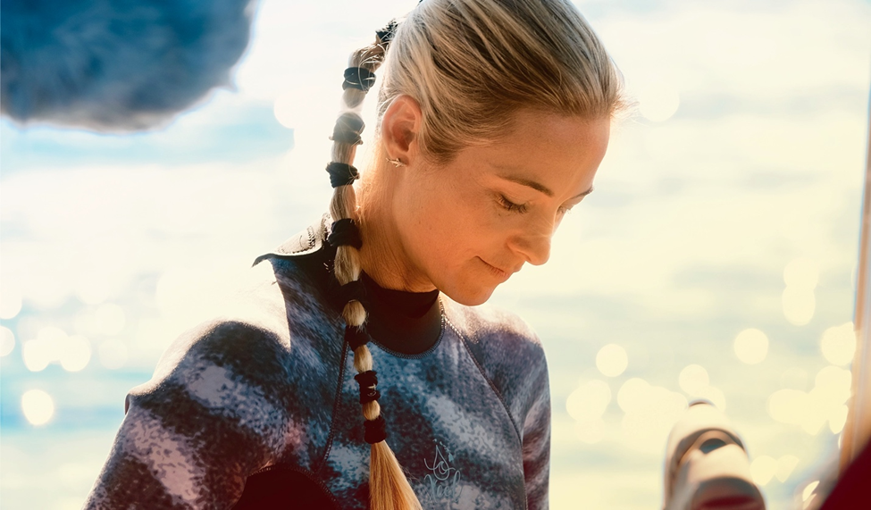 Ocean Ramsey, with her hair in a braided ponytail, focusing intently while wearing a wetsuit.